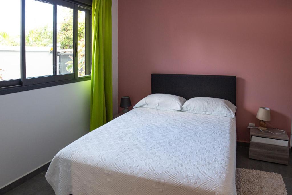 sypialnia z białym łóżkiem z zielonymi zasłonami w obiekcie T2 - 64m2 - Résidence Georgette w mieście Terre Sainte