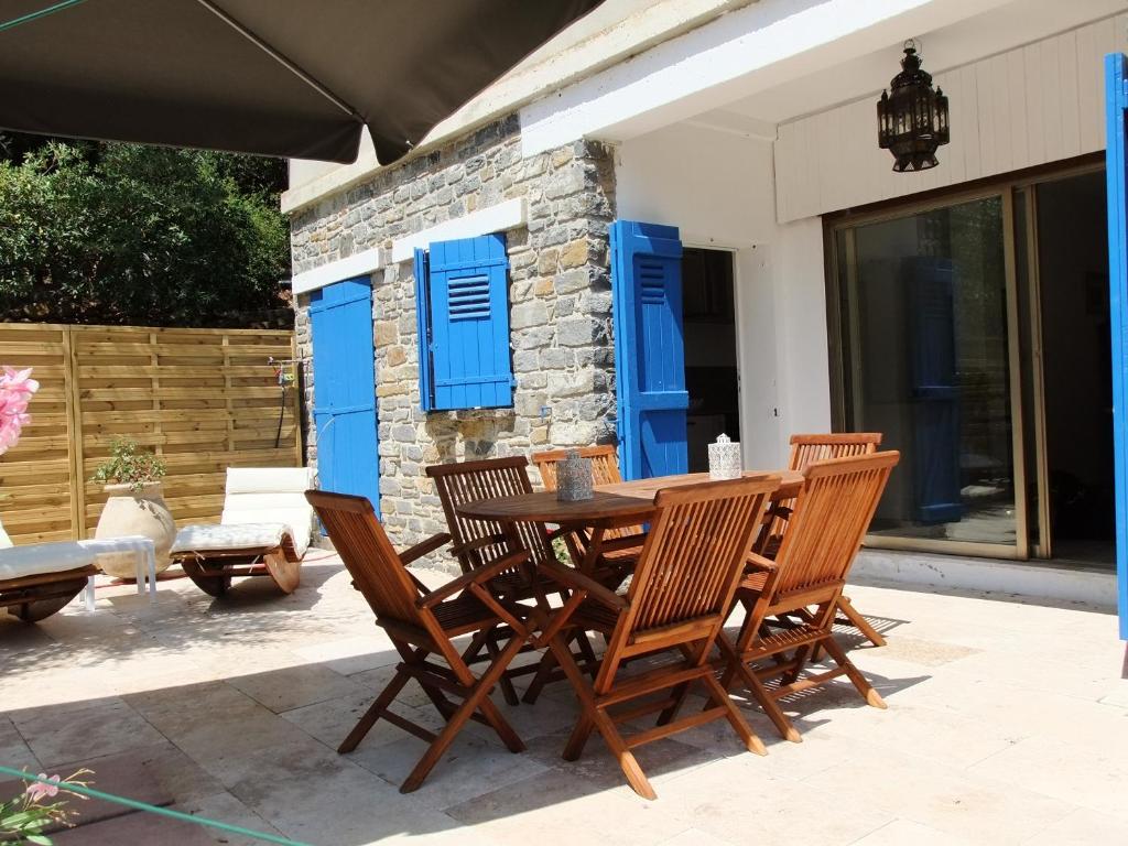 een houten tafel en stoelen op een patio met blauwe luiken bij Lou Pastourel in Le Lavandou