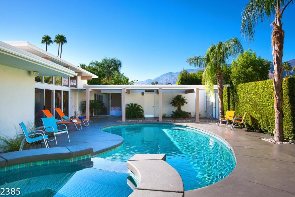 a swimming pool in front of a house at Collins Hideaway in Palm Springs