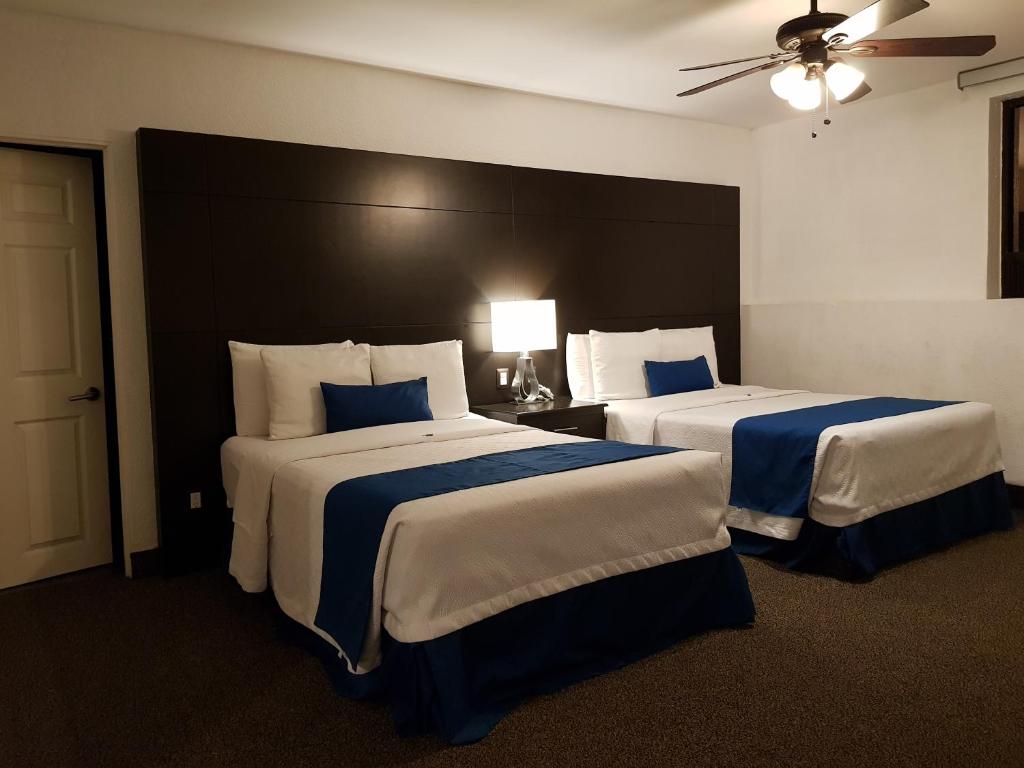 a hotel room with two beds with blue and white sheets at Hotel Principado Tijuana Aeropuerto in Tijuana