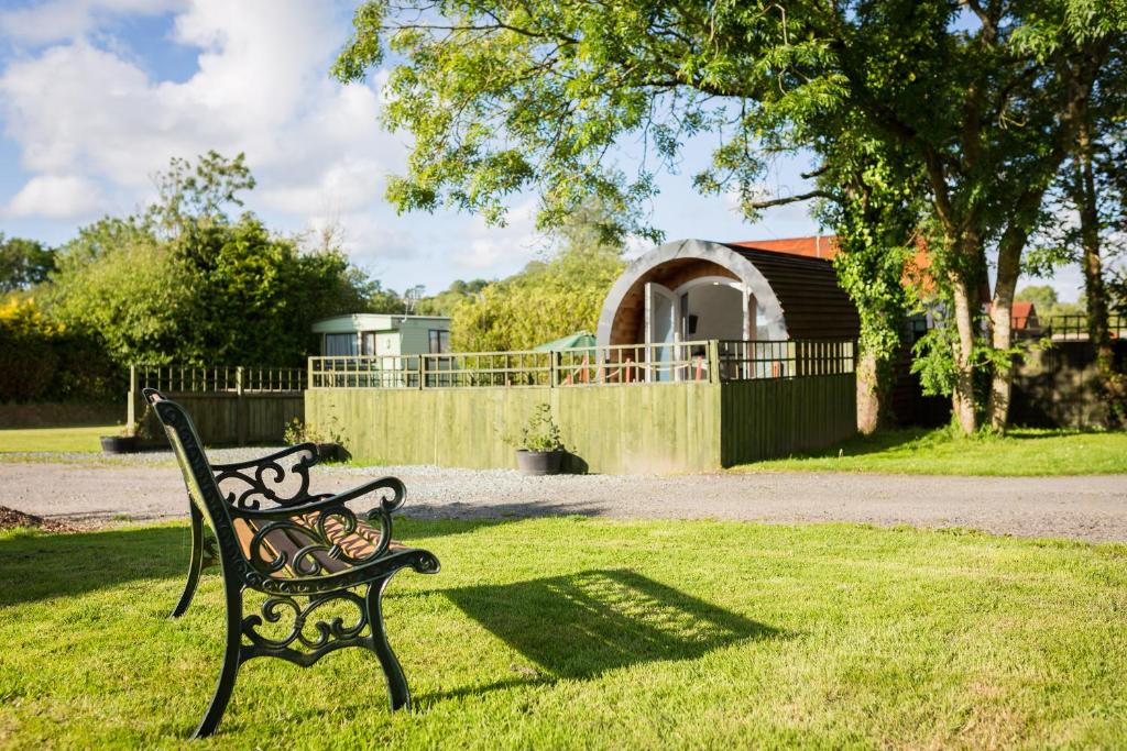 a black bench sitting in the grass in a yard at Buttles Glamping Pod in Saundersfoot