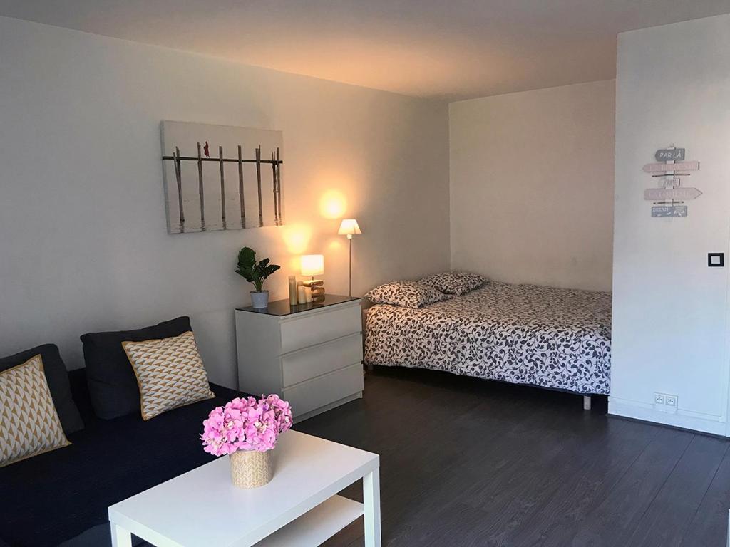 a living room with a bed and a table with flowers at Lovely Flat Champs de Mars Eiffel in Paris