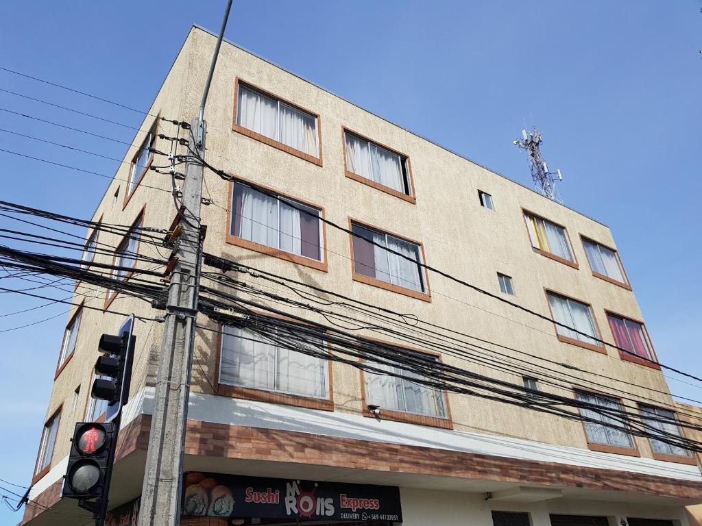 un edificio alto de ladrillo con ventanas y un semáforo en JMJ Departamentos Amoblados Ocarrol, en Rancagua