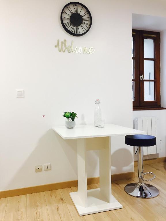 une table blanche dans une pièce avec une horloge sur le mur dans l'établissement The Bancycar, à Annecy