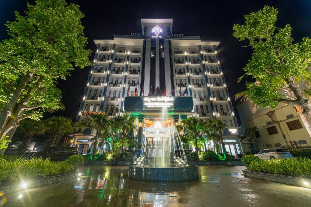 磅同省Kampong Thom Royal Hotel的一座建筑,在晚上前方有一个喷泉