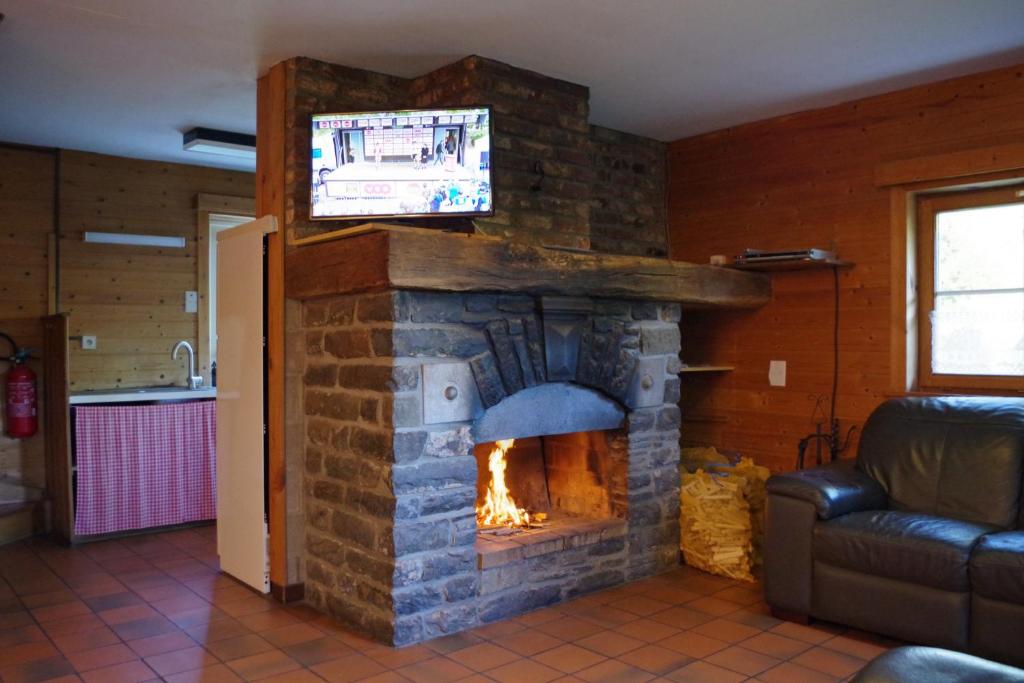 una chimenea de piedra con TV encima. en Au Beolin, en Houffalize