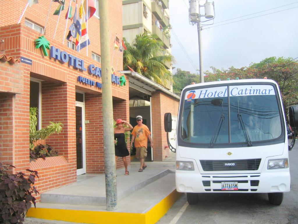 un bus blanc garé devant un bâtiment de l'hôtel dans l'établissement Hotel Catimar, à Maiquetía