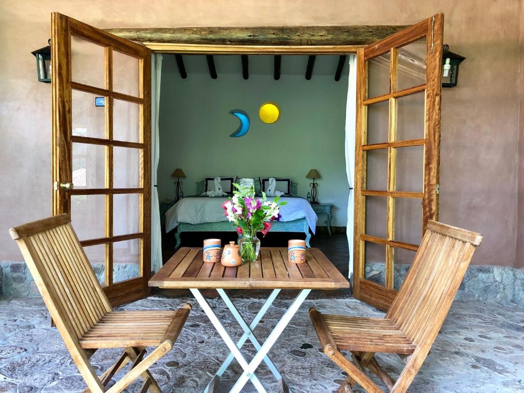 einen Tisch mit 2 Stühlen und ein Bett in einem Zimmer in der Unterkunft Las Casitas del Arco Iris in Urubamba