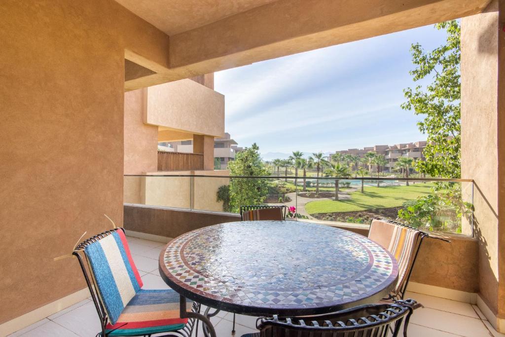 a patio with a table and chairs on a balcony at Coin Lumineux à Prestigia Piscine - vue Atlas in Marrakesh