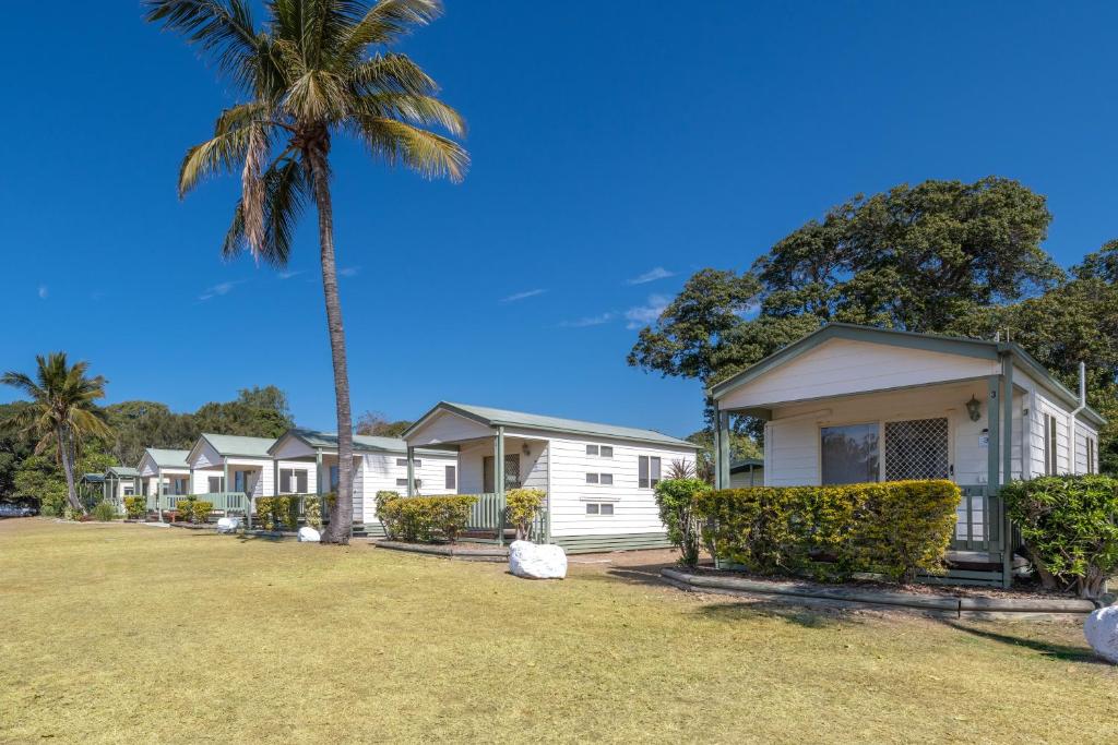 
a white house with a large lawn and trees at BIG4 Breeze Holiday Parks - Bargara in Bargara
