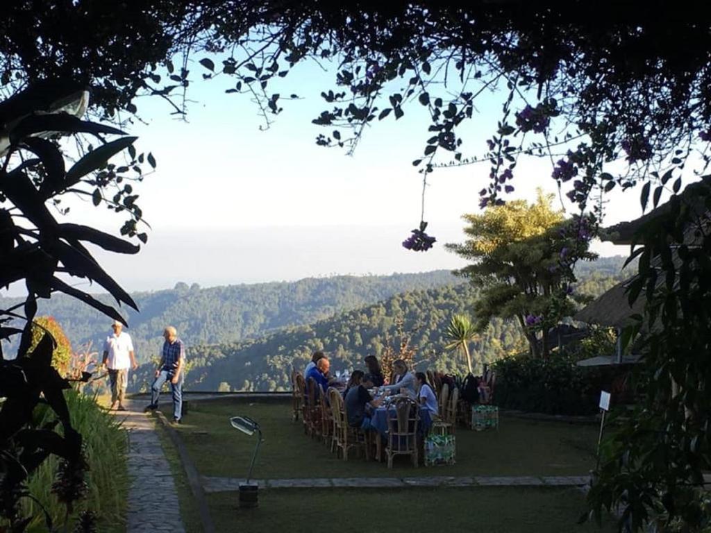 a group of people sitting in chairs on the grass at Puri Lumbung Cottages Restaurant & Spa Munduk in Munduk