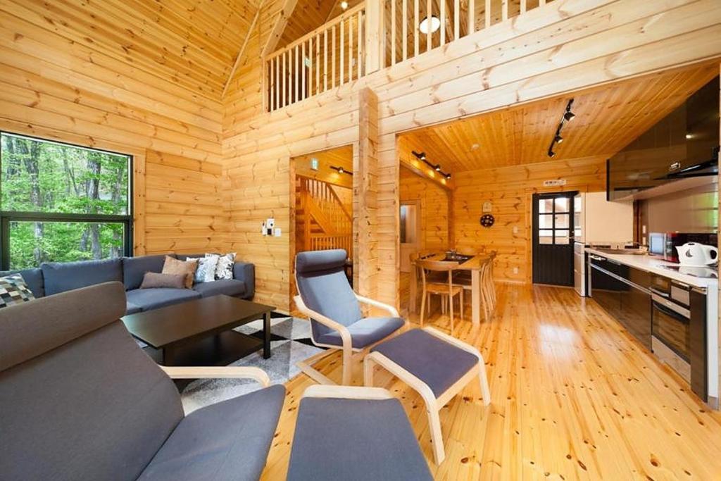 uma sala de estar em cabana de madeira com um sofá e uma mesa em Wadano Woods by Hakuba Hotel Group em Hakuba