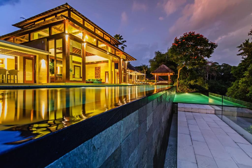 a villa with a swimming pool at night at Villa Champuhan in Tanah Lot