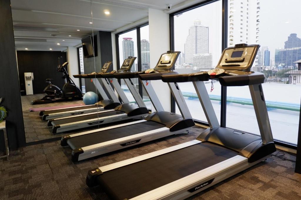 A window-lined cardio room with several treadmills overlooking the city.