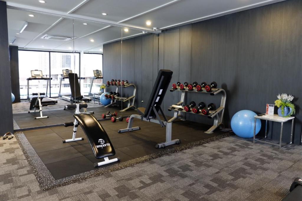 A compact mirrored gym with cardio, strength, and free-weight equipment.