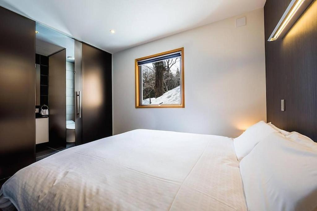 a bedroom with a large white bed and a window at Phoenix Chalets by HHG in Hakuba
