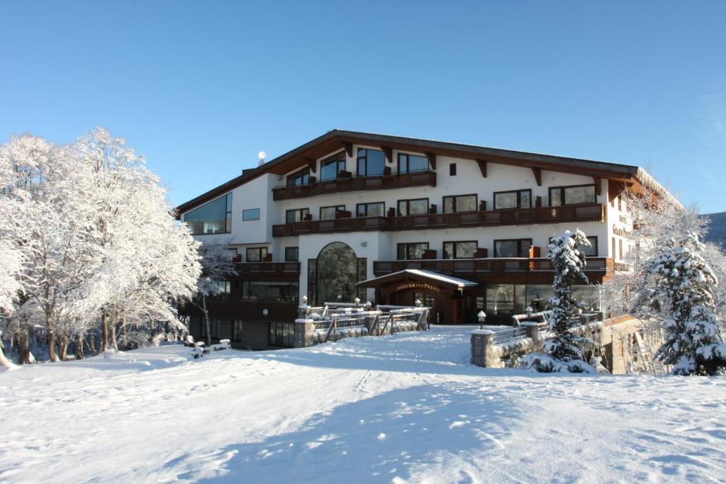 a large building in the snow with trees at Hotel Grand Phenix Okushiga in Yamanouchi