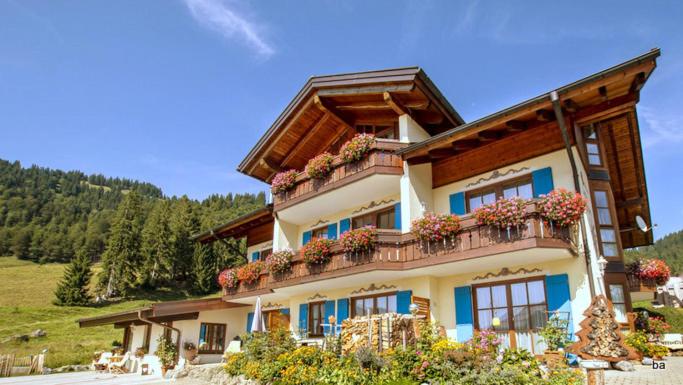 a building with flowers on the balconies of it at Gemütliche Ferienwohnung Bergwiese, 2-Raum, separates Schlafzimmer, schönen Balkon oder Terrasse, Komfort Ausstattung, ruhige Südlage, kostenfrei WLAN, Sauna im Landhaus, Brötchenservice, Parkplatz, Hunde auf Anfrage, E-Tankstelle,Barbaras Wanderheft incl in Balderschwang