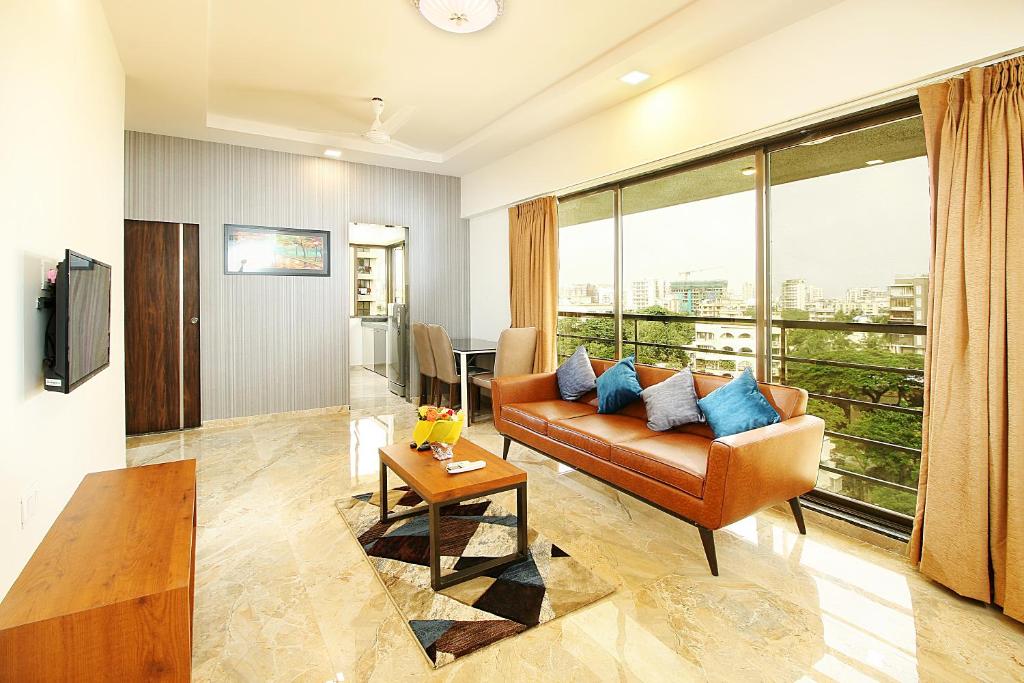 - un salon avec un canapé et une table dans l'établissement Mumbai House Luxury Apartments Santacruz East, Mumbai, à Mumbai