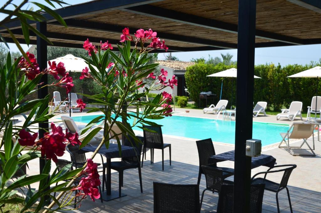 una piscina con mesas, sillas y flores rosas en Serravalle Relais & Country Villa with private pool - Esclusive use en Chiaramonte Gulfi