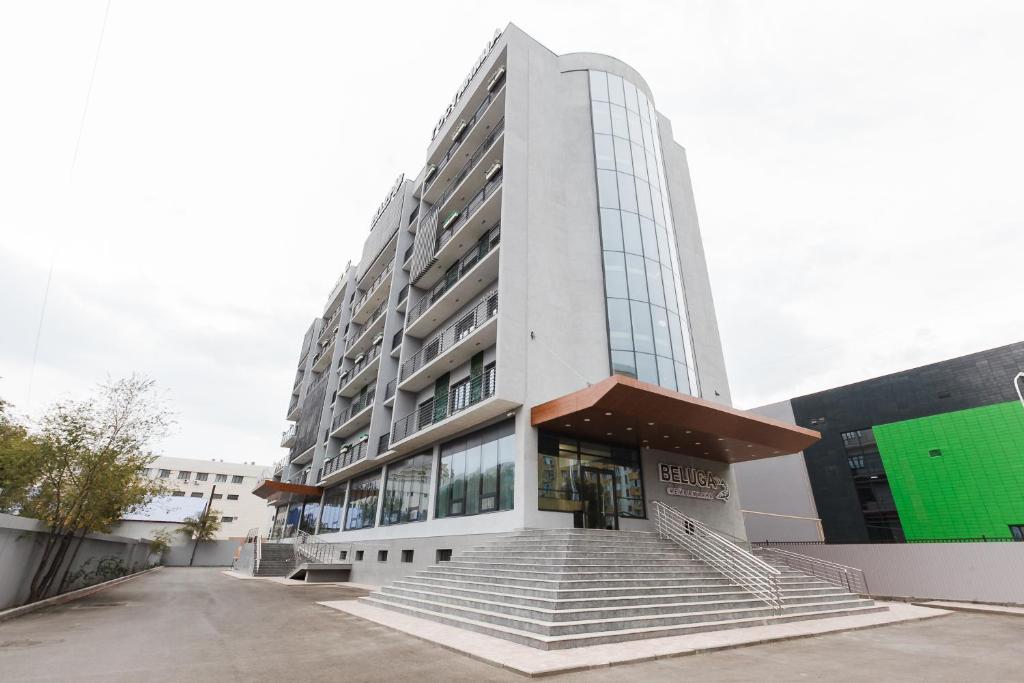 a tall white building with stairs in front of it at Beluga Hotel in Atyrau