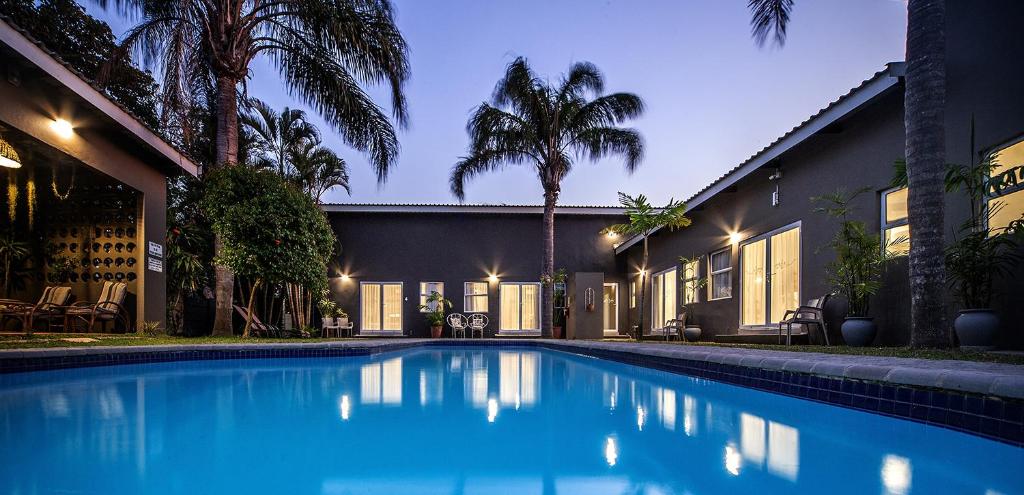 - une piscine en face d'une maison avec des palmiers dans l'établissement iGwalagwala Guest House, à St Lucia