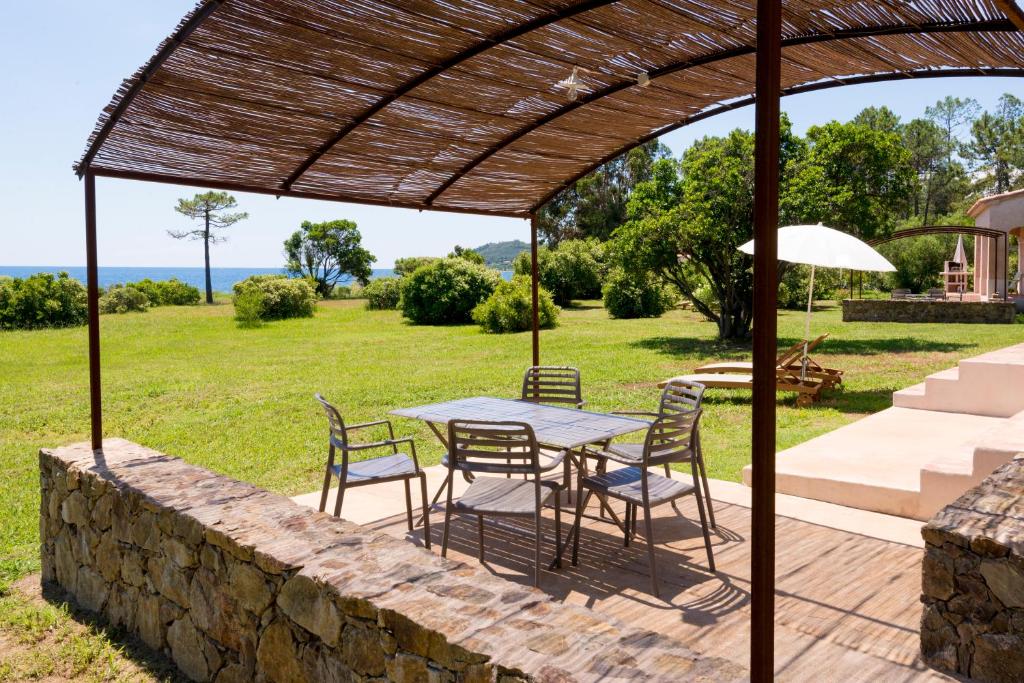 un patio con mesa y sillas bajo una pérgola en Domaine de Pianiccia, en Favone