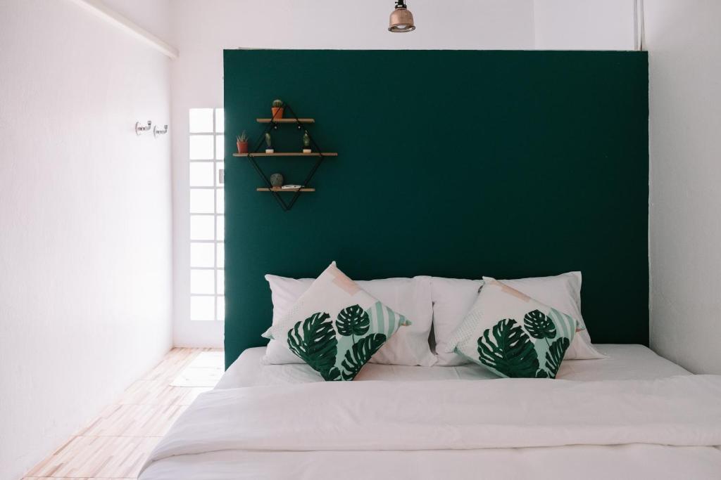 Un dormitorio con una pared verde y una cama con almohadas en Baannokhook Home&Cafe en Surat Thani