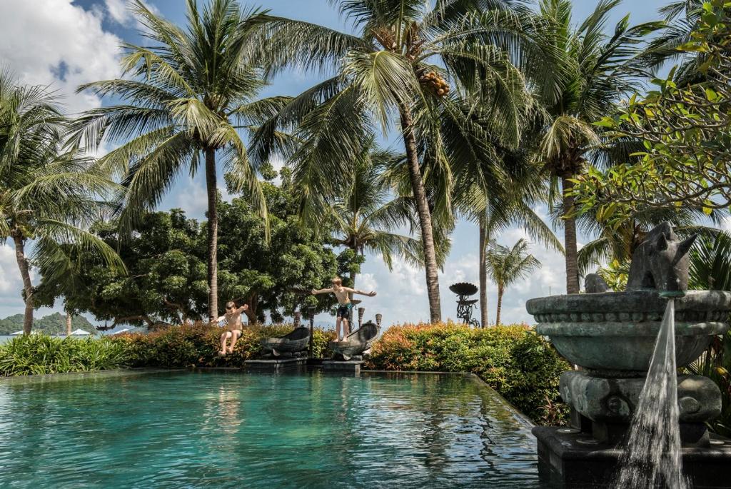 a swimming pool with palm trees and a fountain at Four Seasons Resort Langkawi in Tanjung Rhu