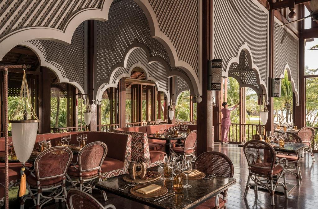 a restaurant with tables and chairs and people in the background at Four Seasons Resort Langkawi in Tanjung Rhu