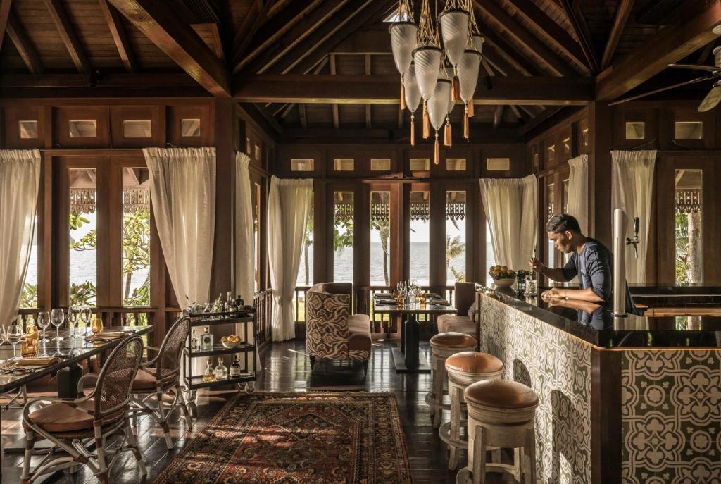 a man sitting at a bar in a restaurant at Four Seasons Resort Langkawi in Tanjung Rhu