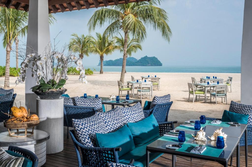 a restaurant with blue chairs and tables on the beach at Four Seasons Resort Langkawi in Tanjung Rhu