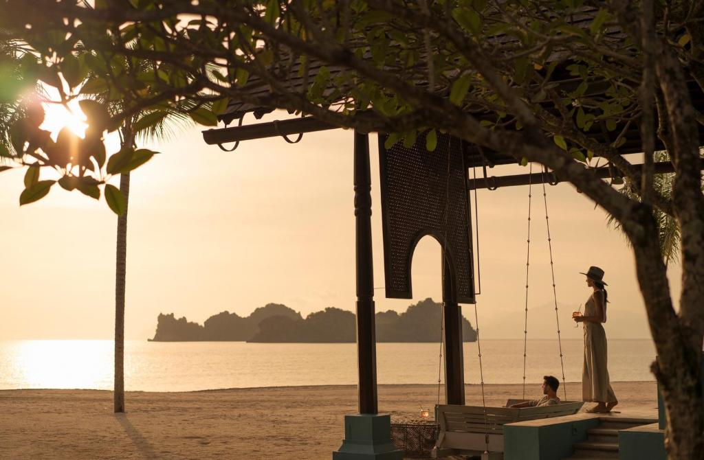 a woman standing on the beach at sunset at Four Seasons Resort Langkawi in Tanjung Rhu