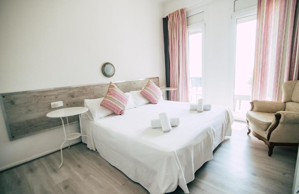 a bedroom with a large white bed and a chair at Hostal La Llagosta in Llafranc