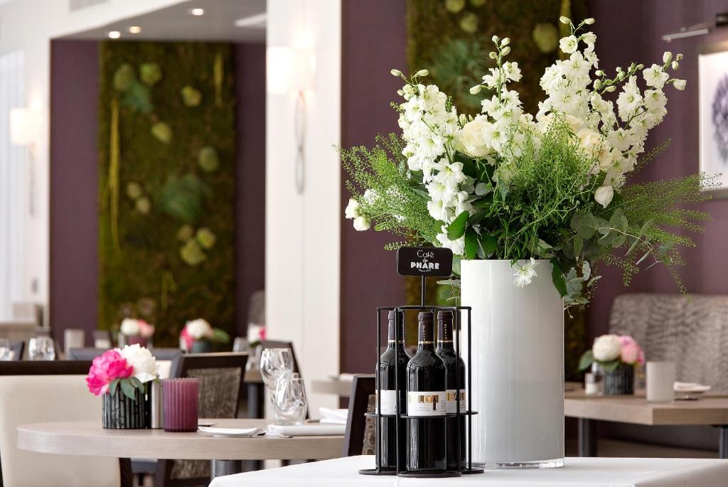 a table with two bottles of wine and a vase of flowers at The Originals Boutique, Hôtel Les Strélitzias in Juan-les-Pins