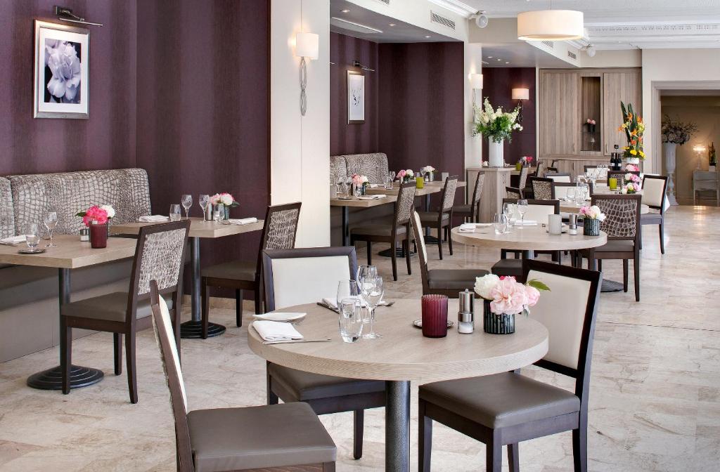 a restaurant with tables and chairs with flowers on them at The Originals Boutique, Hôtel Les Strélitzias in Juan-les-Pins