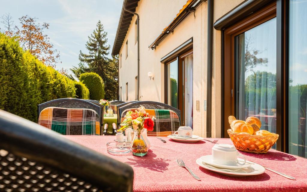 Hotel garni Steinfeld في وينر نويشتاد: طاولة مع قطعة قماش وردية على طاولة مع الزهور والمزاد