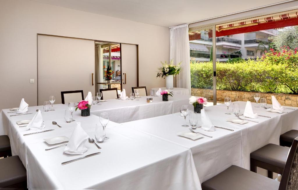 a set of tables with white tablecloths and flowers at The Originals Boutique, Hôtel Les Strélitzias in Juan-les-Pins