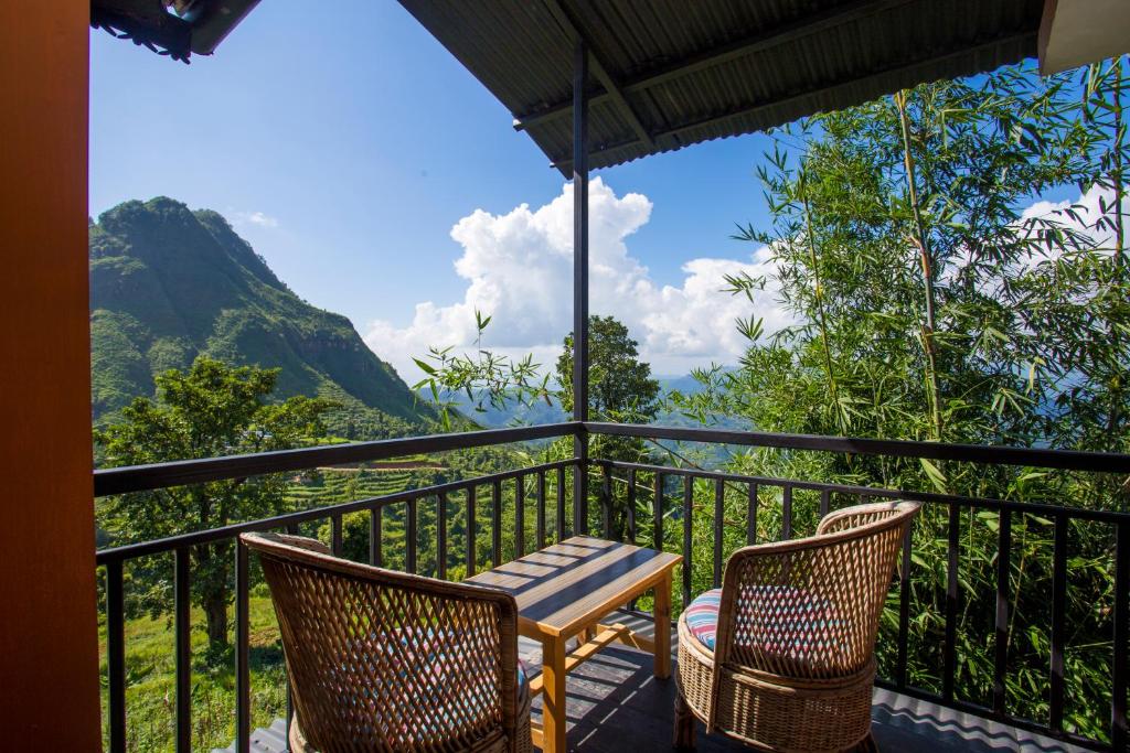 a balcony with chairs and a table and a view at Depche Village Resort in Bandipur