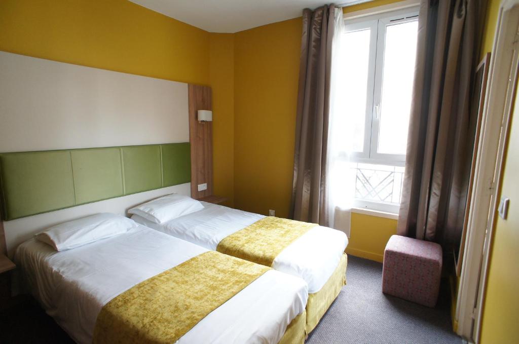 a hotel room with two beds and a window at Hôtel De France in Boulogne-Billancourt