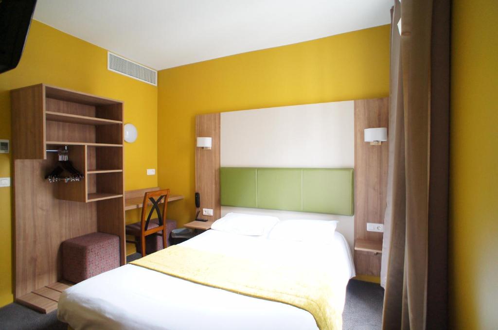 a bedroom with a bed and a desk at Hôtel De France in Boulogne-Billancourt