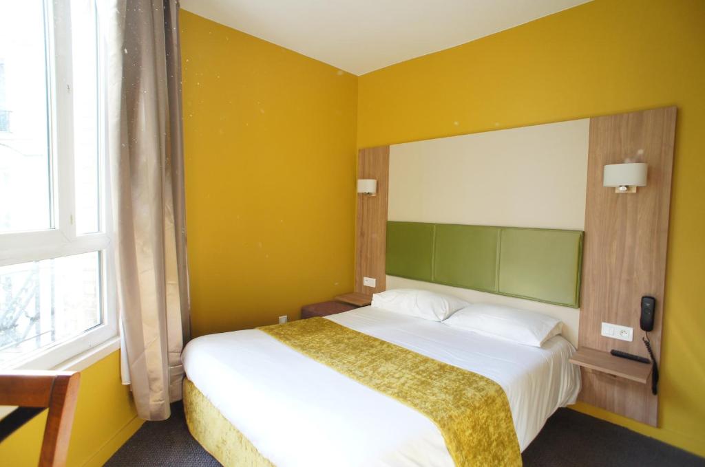a bedroom with a bed with a yellow wall at Hôtel De France in Boulogne-Billancourt