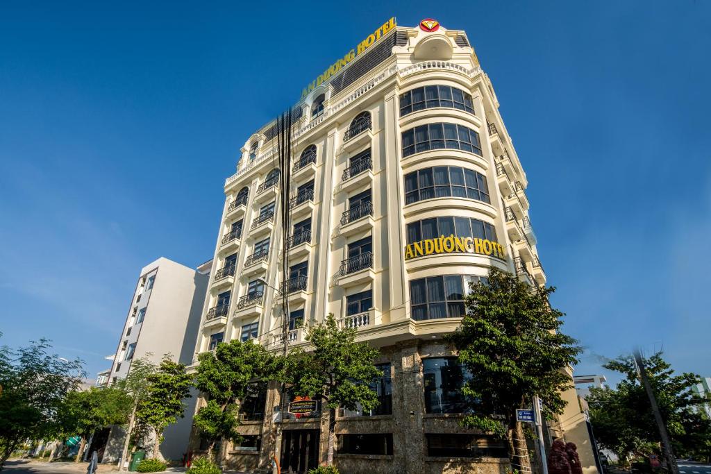 a tall white building with a yellow sign on it at An Dương Hotel & Apartment in Da Nang