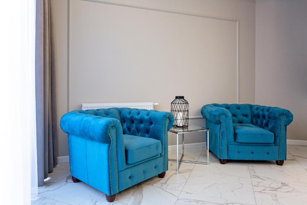 two blue chairs and a side table in a room at Apartamenty Prestiż 93 in Koszalin