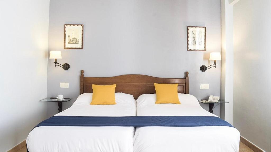 sypialnia z dużym łóżkiem z 2 żółtymi poduszkami w obiekcie Villa Soledad w mieście Torrejón de Ardoz