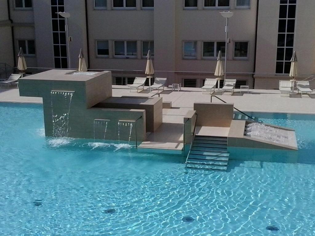 a swimming pool with stairs and chairs in a building at Hotel Terme Marine Leopoldo II TERME & SPA in Marina di Grosseto