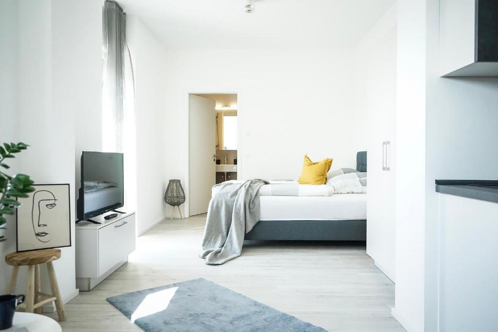 een witte slaapkamer met een bed en een televisie bij Prime Park Apartment Aschaffenburg in Aschaffenburg