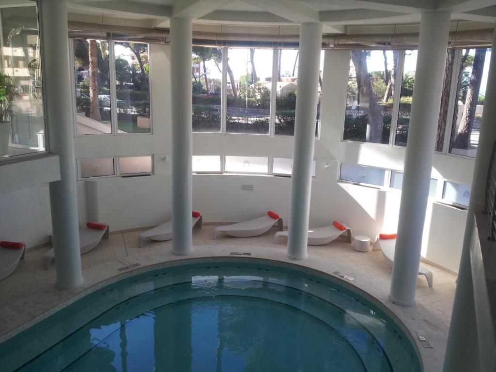 a swimming pool in a building with columns and windows at Hotel Terme Marine Leopoldo II TERME & SPA in Marina di Grosseto