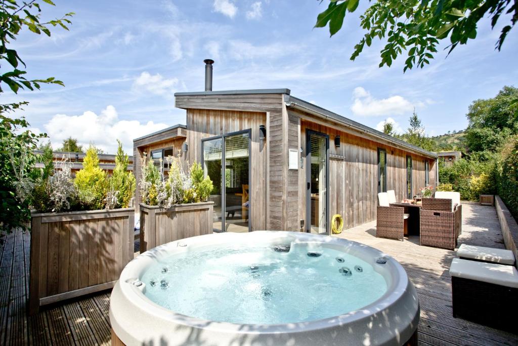 a hot tub on a deck next to a house at The Retreat, Strawberryfield Park in Cheddar