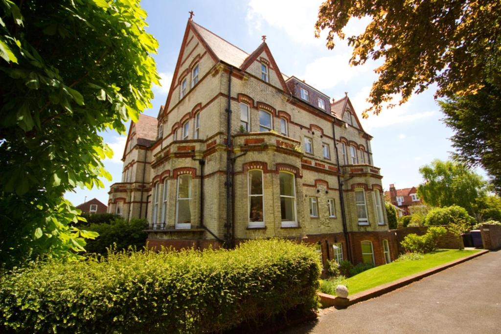 un viejo edificio de ladrillo con un seto delante de él en Littledale Haven en Eastbourne